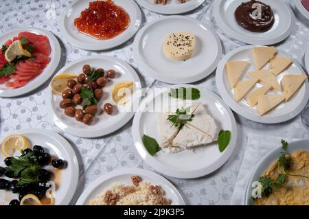 Un tavolo per la colazione con una varietà di cibi. Ci sono alimenti come uova, burro, miele, marmellata, tè, pane, formaggio, pomodori, omelette sul tavolo. Foto Stock