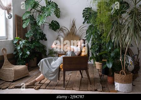 Soddisfatto calmo donna fiorista rilassarsi in giardino interno godere di equilibrio mentale e benessere a casa Foto Stock