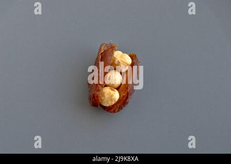 Hurma secco nutriente biologico fresco datteri chicchi di medjool, nocciole poste all'interno della data, in un piatto grigio Foto Stock