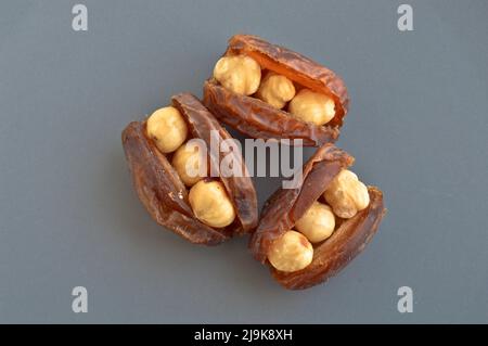 Hurma secco nutriente biologico fresco datteri chicchi di medjool, nocciole poste all'interno della data, in un piatto grigio Foto Stock