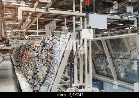 Vista laterale della sala di produzione con supporti per la produzione di cablaggi elettrici per automobili in fabbrica moderna. Foto Stock