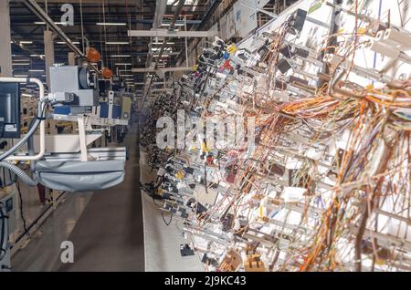 Vista laterale della sala di produzione con supporti per la produzione di cablaggi elettrici per automobili in fabbrica moderna. Foto Stock