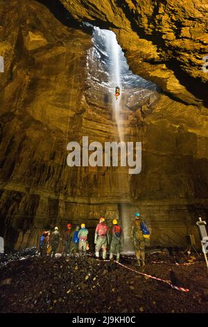 All'interno della vasta caverna principale di Gill pothole gaping, Ingleborough, Yorkshire Dales National Park, Regno Unito. Una speleologia si vede scendere in un sedile a gabbia. Foto Stock