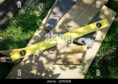 Un set di attrezzi di carpenteria si trova sull'erba. Livello, vecchie tavole. Foto Stock