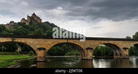 Castelnaud-la-Chapelle, Francia - 12 maggio, 2022: Il castello di Castelnaud-la Chapelle con il ponte Route de la Pagaie sul fiume Dordogna Foto Stock