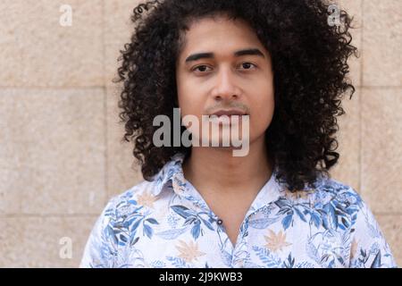 Giovane adulto con capelli ricci lunghi in città Foto Stock