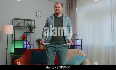 L'uomo povero sconvolto che mostra tasche vuote dentro fuori, non avendo soldi, fallimento, debiti, problema di povertà Foto Stock
