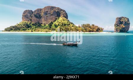 turista su una barca a coda lunga tailandese che guida attraverso le molte isole del mare delle andamane in Krabi Thailandia in una mattinata di sole vicino all'isola di Ko Poda Foto Stock