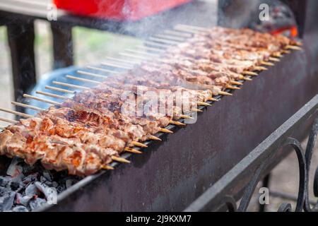 Pezzi di carne storti su spiedini di metallo sulla griglia al tramonto Foto Stock