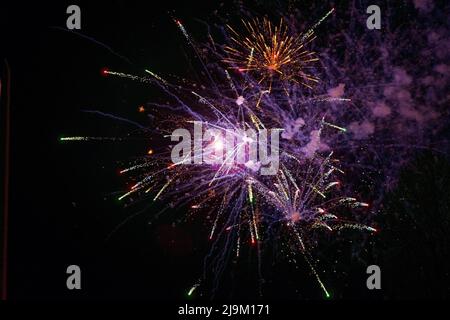 Luminosi e bellissimi fuochi d'artificio festosi di colore giallo e lilla, con foschia, nel cielo notturno. Foto di alta qualità Foto Stock