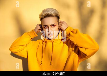 Giovane donna hipster in felpa gialla con cappuccio ritratto Foto Stock