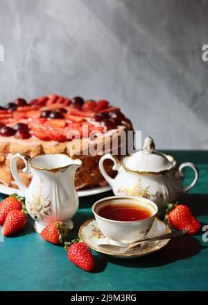 Torta di fragole e tazza di tè nero su un tavolo. Foto Stock