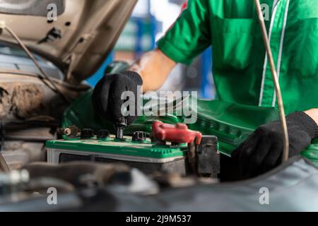 Il meccanico automatico controlla la batteria per i clienti che vengono a utilizzare il servizio di sostituzione della batteria presso il negozio. Foto Stock