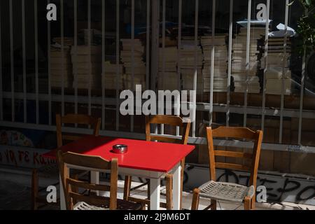 Un tavolo rosso e sedie si trovano sul marciapiede di fronte ad un negozio di libri Foto Stock