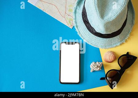 Kit da viaggio con cappello, tessera da viaggio, smartphone e occhiali da sole su sfondo blu Foto Stock