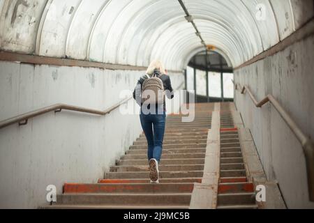 La ragazza entra nel tunnel. La donna sale le scale. La persona cammina lungo l'attraversamento pedonale sopra l'autostrada. Foto Stock