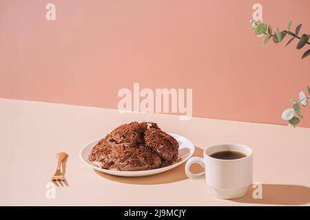 Torta sul piatto con forchetta dorata e tazza di caffè sul tavolo su sfondo rosa Foto Stock