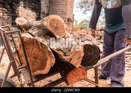 Uomo irriconoscibile che porta una pila di legna da ardere su un carrello di metallo per accendere un forno di mattoni in nicaragua Foto Stock