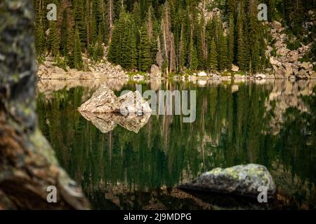 Il piccolo Boulder si riflette nel Green of Haiyaha Lake nel Rocky Mountain National Park Foto Stock