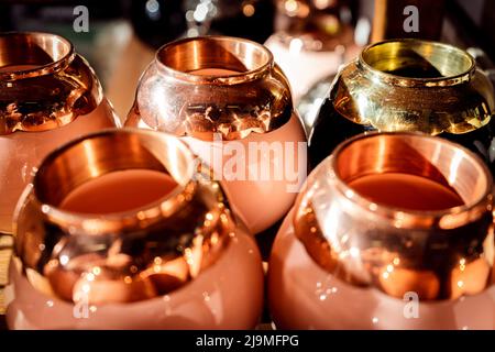 Collezione di coppe in zucca con bordi in argento fatti a mano posti su scaffale in officina Foto Stock