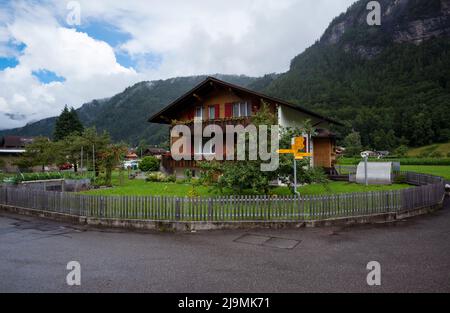 Vista di una splendida casa in legno alpina con un bellissimo e colorato giardino e recinzione catturati ad Aareschlucht, Svizzera. Foto Stock