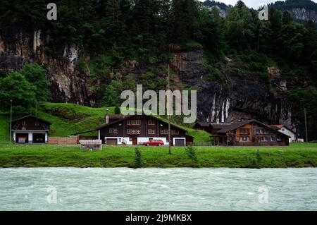 Vista delle case di chalet in legno splendidamente decorate con fiori che si affacciano sul fiume Aare catturate ad Aareschlucht 'Svizzera. Foto Stock