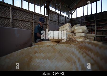 Un uomo prepara la tradizionale scatola di cibo di bambù chiamata 'besek' al confezionamento prima della spedizione al villaggio di Brajan a Sleman, Yogyakarta, Indonesia Foto Stock