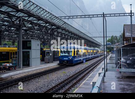 Vista del treno blu-giallo della oberland Bahn Bernese al binario della stazione di Interlaken Ost, Svizzera. Foto Stock