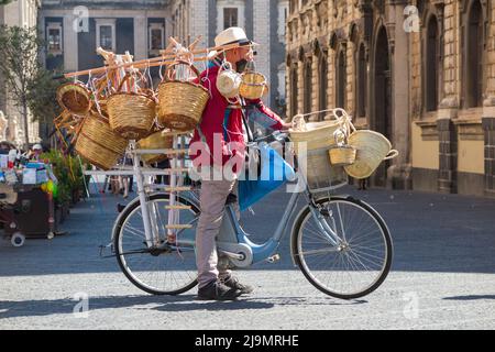 Uomo medio/anziano, siciliano locale, uomo bric-a-brac mobile in bicicletta che vende cesti di vimini tessuti ai turisti, dalla sua bicicletta, in Piazza del Duomo, Catania, Sicilia. Italia (129) Foto Stock