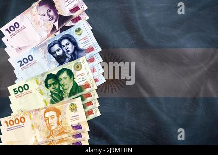 Le fatture argentine del peso e la bandiera argentina sullo sfondo Foto Stock