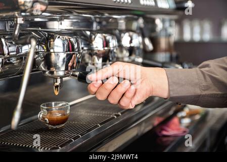 Il barman classico prepara a mano l'espresso italiano alla moderna macchina da caffè nella caffetteria della moda - concetto di cibo e bevande con bartenia professionale Foto Stock