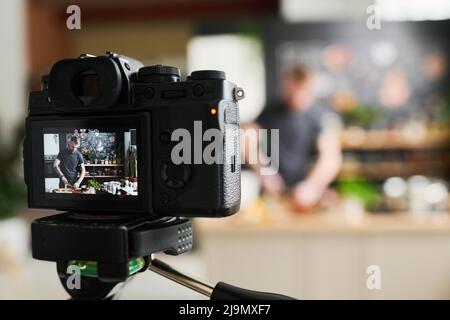 Primo piano focus selettivo sulla fotocamera scattata dallo chef maschile caucasico moderno che prepara una lezione di cucina online Foto Stock