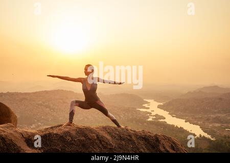 Yoga in Hampi tempio copyspase al Sunset.Travel vacanza copia spase signora con elegante tuta Foto Stock