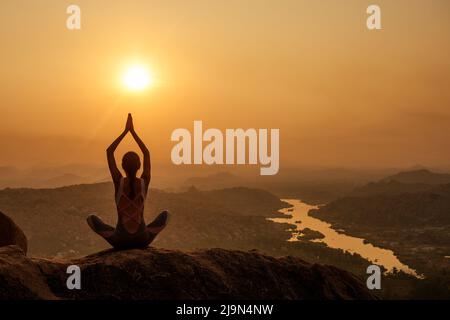 Yoga in Hampi tempio copyspase al Sunset.Travel vacanza copia spase signora con elegante tuta Foto Stock