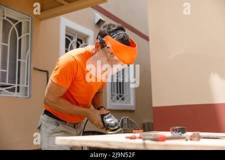 Un uomo nel suo cantiere è impegnato in un lavoro di fabbro. Hobby, in un laboratorio domestico. Foto Stock