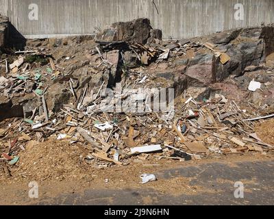 un muro di pietra in una discarica di rifiuti. rifiuti di legno in una discarica. Foto Stock