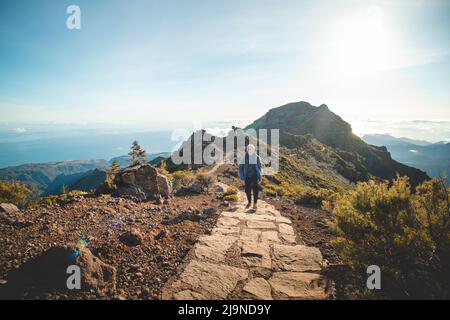 Sentiero escursionistico sotto l'Encumeada Baixa con una destinazione sulla montagna più alta di Madeiras, Pico Ruivo. Il sole splende sul lato di Madeira Foto Stock