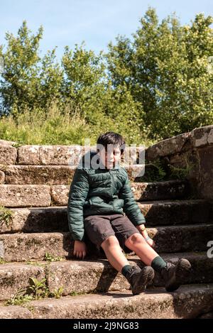 ragazzino seduto su una scala in pietra in spagna Foto Stock