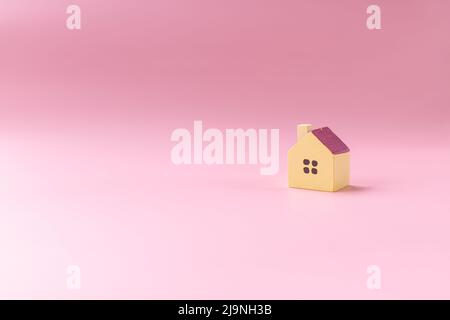 Design semplice e minimalista con casa giocattolo in miniatura isolata su sfondo bianco. Ipoteca proprietà assicurazione sogno casa concetto.