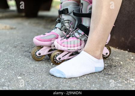 Donna al parco che mette su pattini che si prepara ad avere divertimento Foto Stock