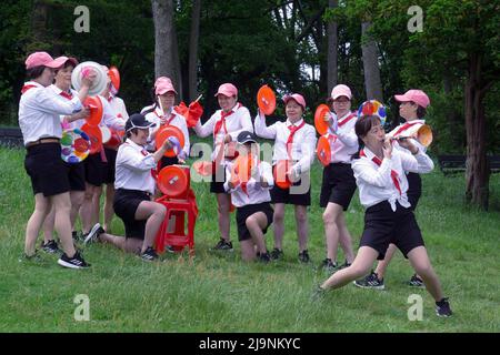 Un gruppo di artisti asiatici americani di mezza età si prepara per una performance per i bambini. In un parco a Queens, New York City. Foto Stock