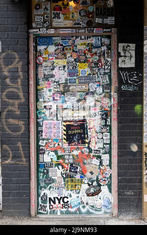 Una porta completamente coperta di adesivi, Street art, graffiti e tag. Su Wycoff Avenue a Bushwick, Brooklyn, New York Foto Stock