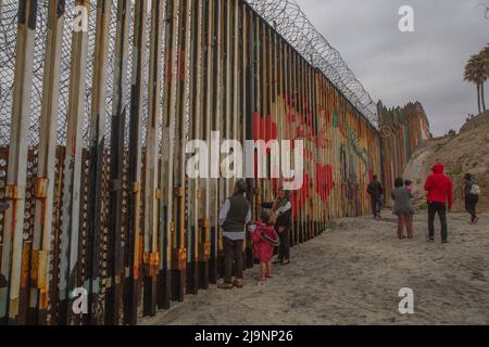 Tijuana, Messico. 21st maggio 2022. Le famiglie osservano curiosamente il muro che sorge sulla spiaggia al confine tra Messico e Stati Uniti. Il titolo 42, pandemica regolamentazione che limita l'immigrazione dal Messico agli Stati Uniti, rimane in vigore per ora. Credit: Aimee Melo/dpa/Alamy Live News Foto Stock