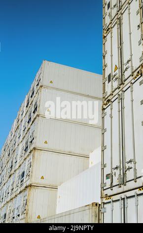 Grandi pile di contenitori refrigerati bianchi contro un cielo azzurro Foto Stock