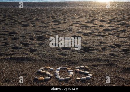 SOS significato salvare le nostre anime messaggio fatto con pietre sulla spiaggia Foto Stock