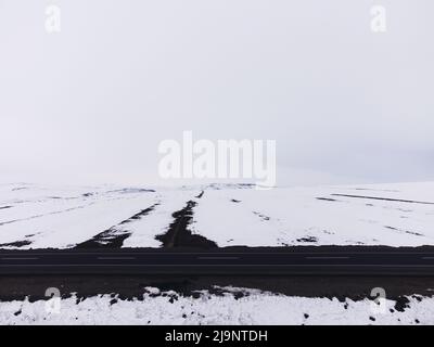 Vista laterale di una strada semitra con corsie gialle e neve in inverno. Foto Stock