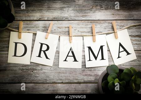 Un insieme di schede stampate che ortografia il DRAMMA di parola su uno sfondo di legno invecchiato. Foto Stock