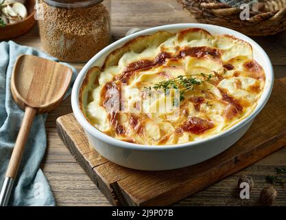 gratin di patate appena sfornate su un rustico tavolo da cucina in legno Foto Stock