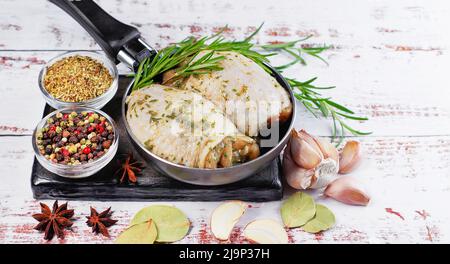 Cosce di pollo crude marinate in salsa di erbe con rosmarino fresco, spezie. Cosce di pollo con spezie, aglio. Foto Stock