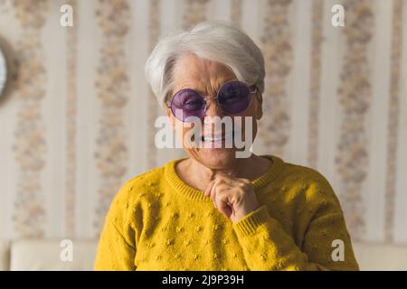 nonna carina allegra con occhiali da sole viola ridendo ampiamente medio closeup indoor senior concetto di supporto. Foto di alta qualità Foto Stock